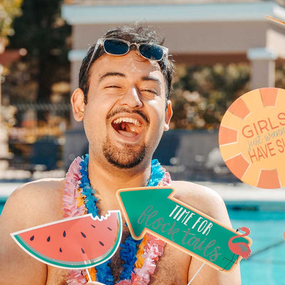 man with party signs in hand enjoying pool party in hawaiian clothes