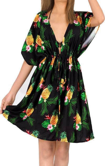 woman styled in a black short coverup with tropical leaves and pineapple bunch print