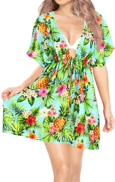 woman wearing a tropical print with hawaiian hibiscus, leaves, pineapple luau party coverup dress